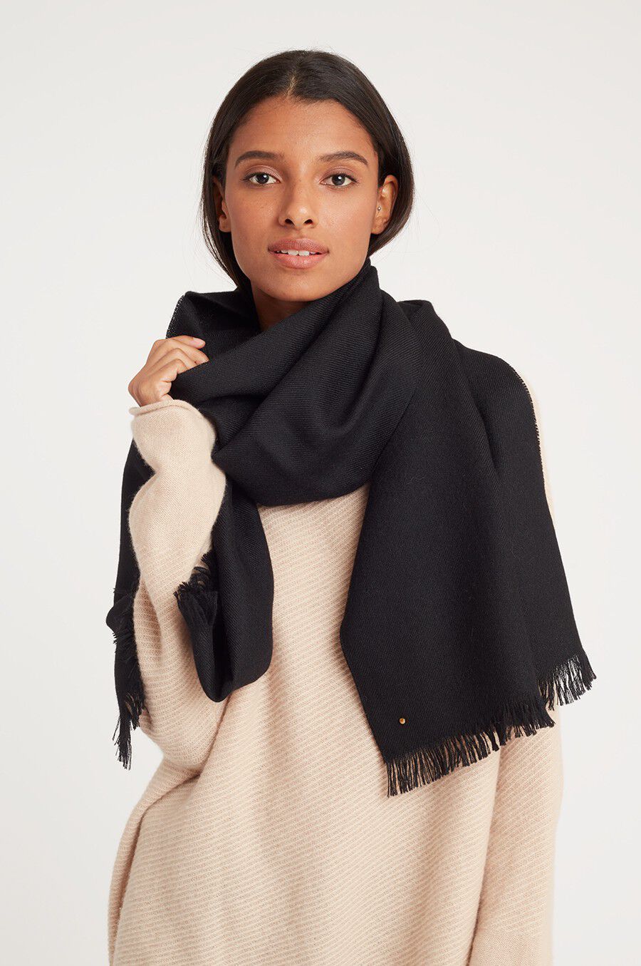 Alpaca Scarf Woman wearing a large scarf over a sweater, looking at the camera.