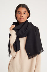 Woman wearing a large scarf over a sweater, looking at the camera.