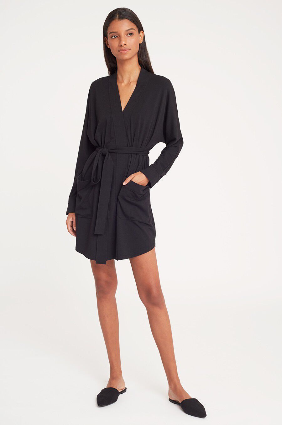 Woman standing in a belted dress and flat shoes