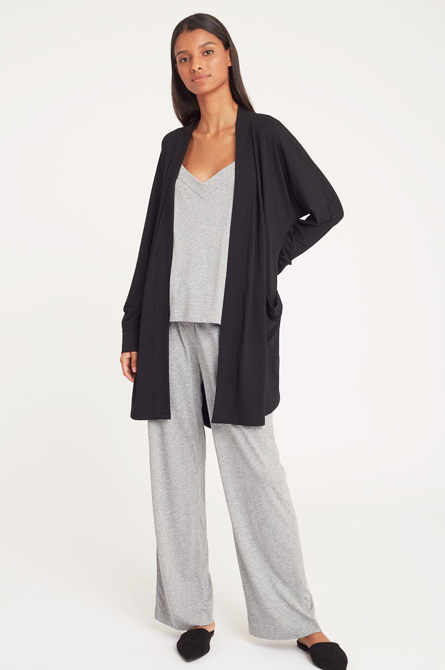 Woman standing in a casual outfit with cardigan, top, and pants.