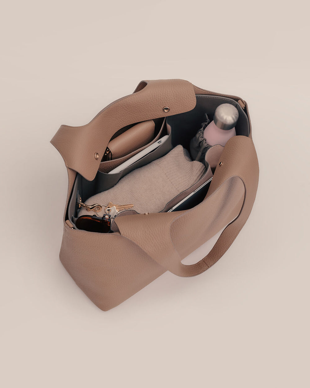 Open handbag with contents including a bottle and small pouch visible.