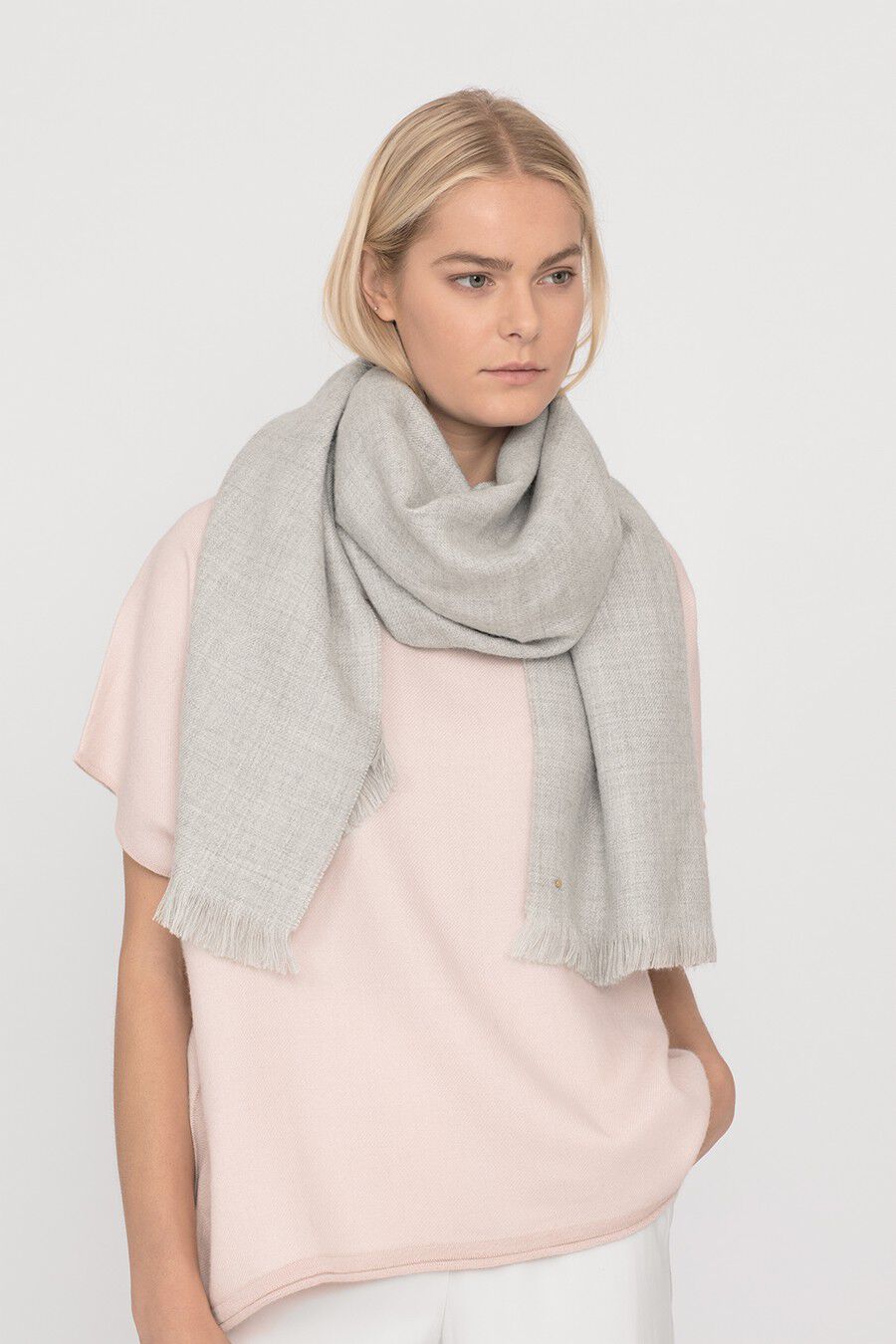 Woman wearing a scarf and top, looking to the side.