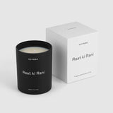 Candle in a container next to its packaging box with text labels.