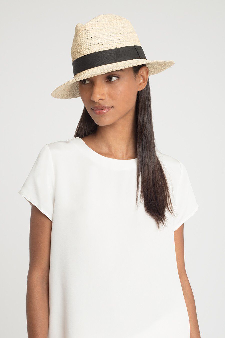 Folding Panama Hat Woman wearing a hat and a top, looking to the side.