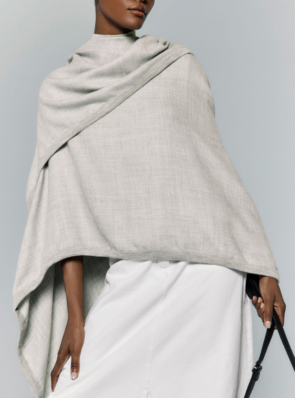 Woman wrapped in a shawl, holding a strap, looking to one side.
