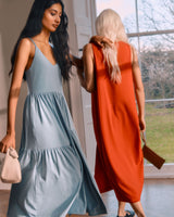 Two women walking through a doorway, one guiding the other by the shoulder.