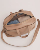 Bag partially unzipped with jeans and a sweater inside.