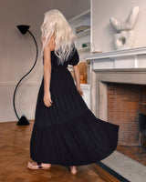 Woman in a long dress walking in a room with a fireplace and sculptures.