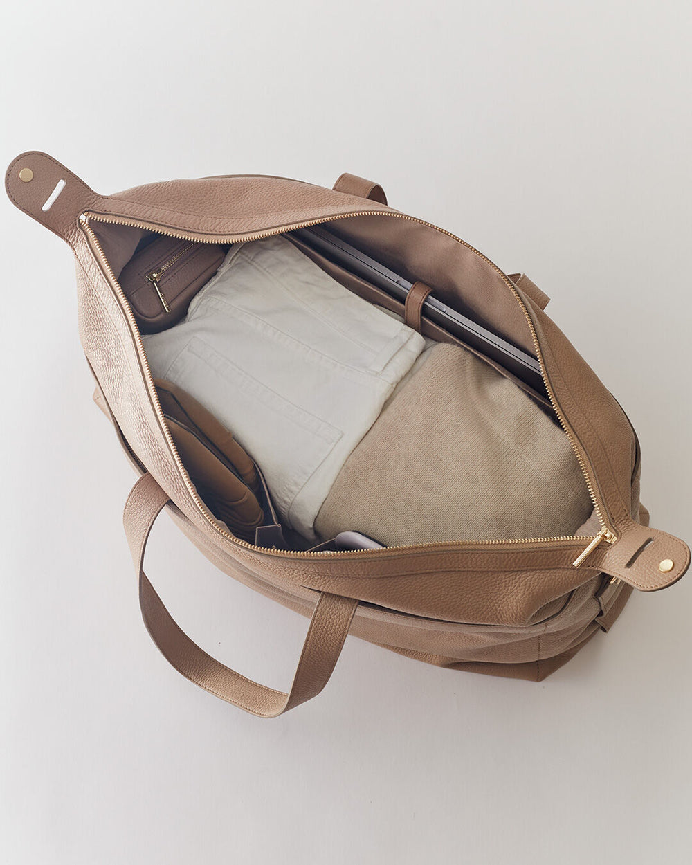 Open bag with a laptop and folded clothes inside.