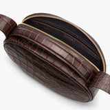 Close-up view of a textured belt bag with an open zipper.