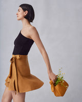 Woman standing holding a bag with a plant inside.