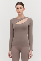 Woman in long sleeve top with asymmetrical neckline standing straight