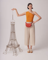 Woman standing next to a model of the Eiffel Tower, holding its top.