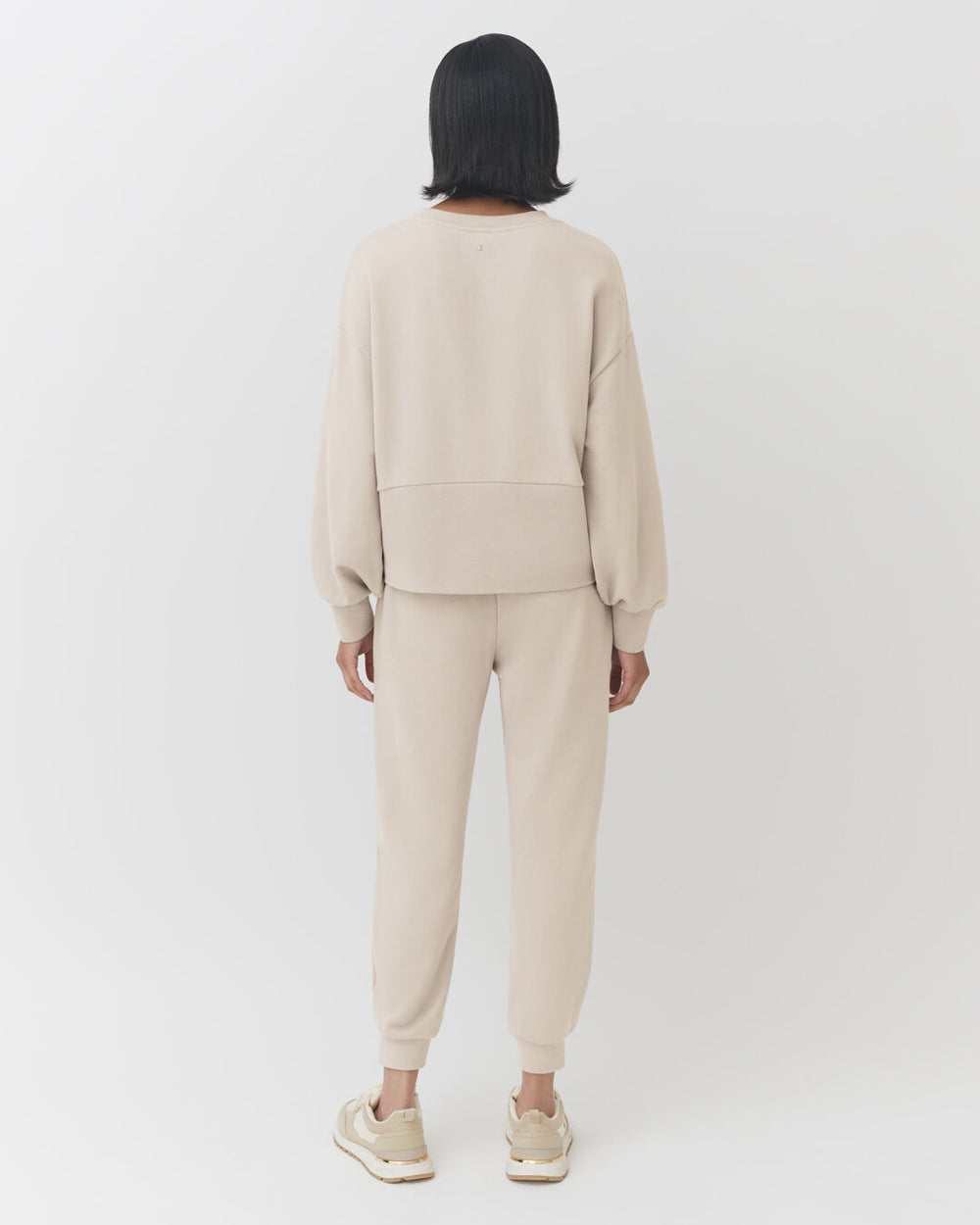 Terry Balloon Sleeve Sweatshirt Woman standing facing away, wearing a casual outfit and sneakers.