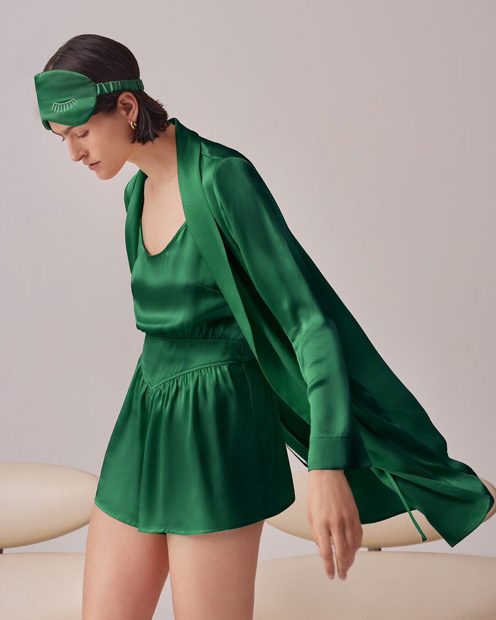 Woman in a coordinated outfit and headband leaning on a couch.