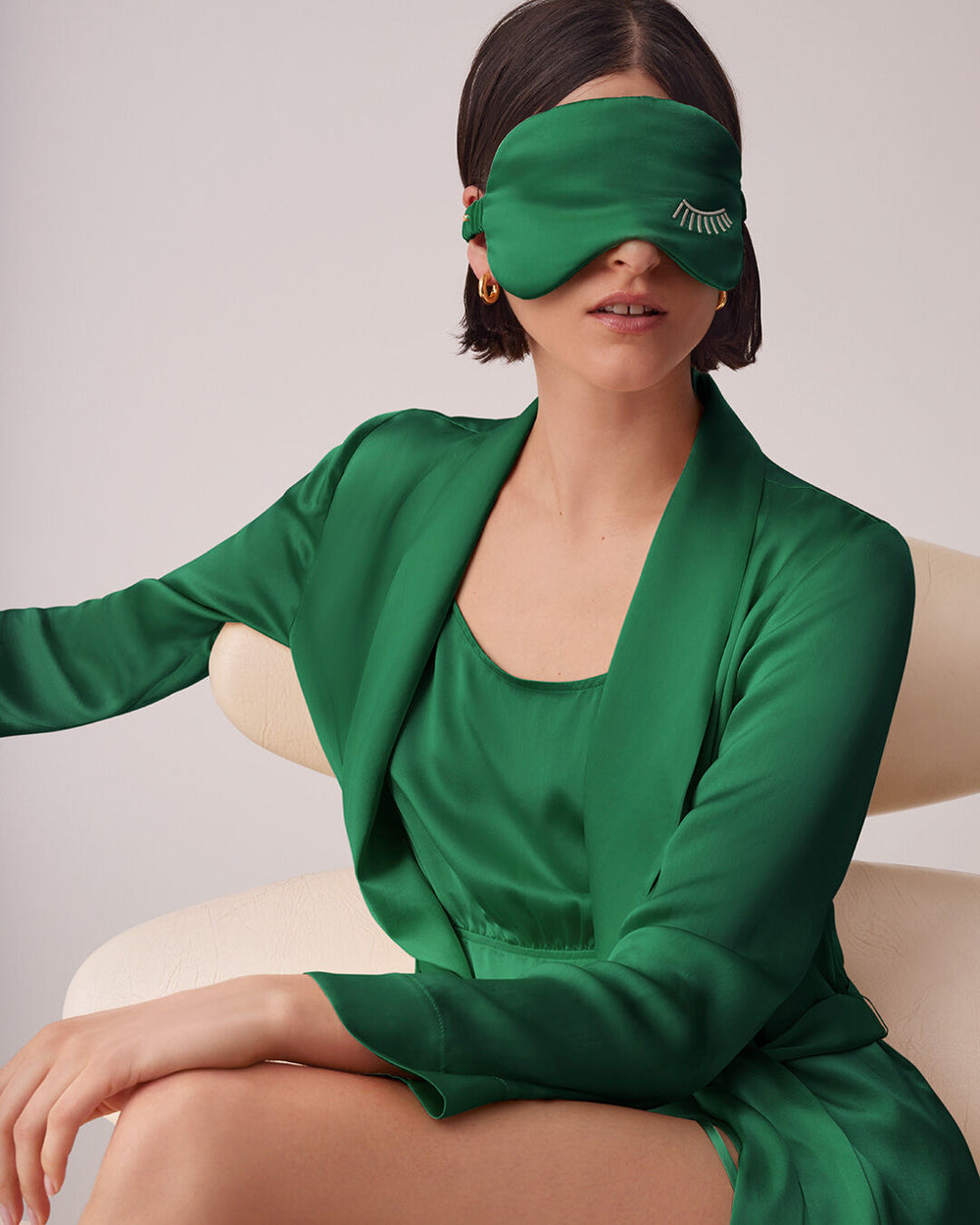 Woman seated on a chair wearing a blindfold and outfit.
