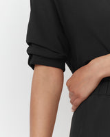 Person standing with hand on hip, close-up view of arm and torso