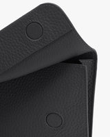 Close-up of a textured handbag flap with two snap buttons.