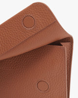 Close-up view of a textured handbag flap with two snap buttons.