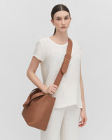 Woman standing with a handbag over her shoulder.