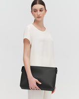 Woman standing with a large shoulder bag.