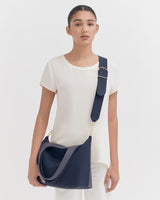 Woman standing and holding a shoulder bag.