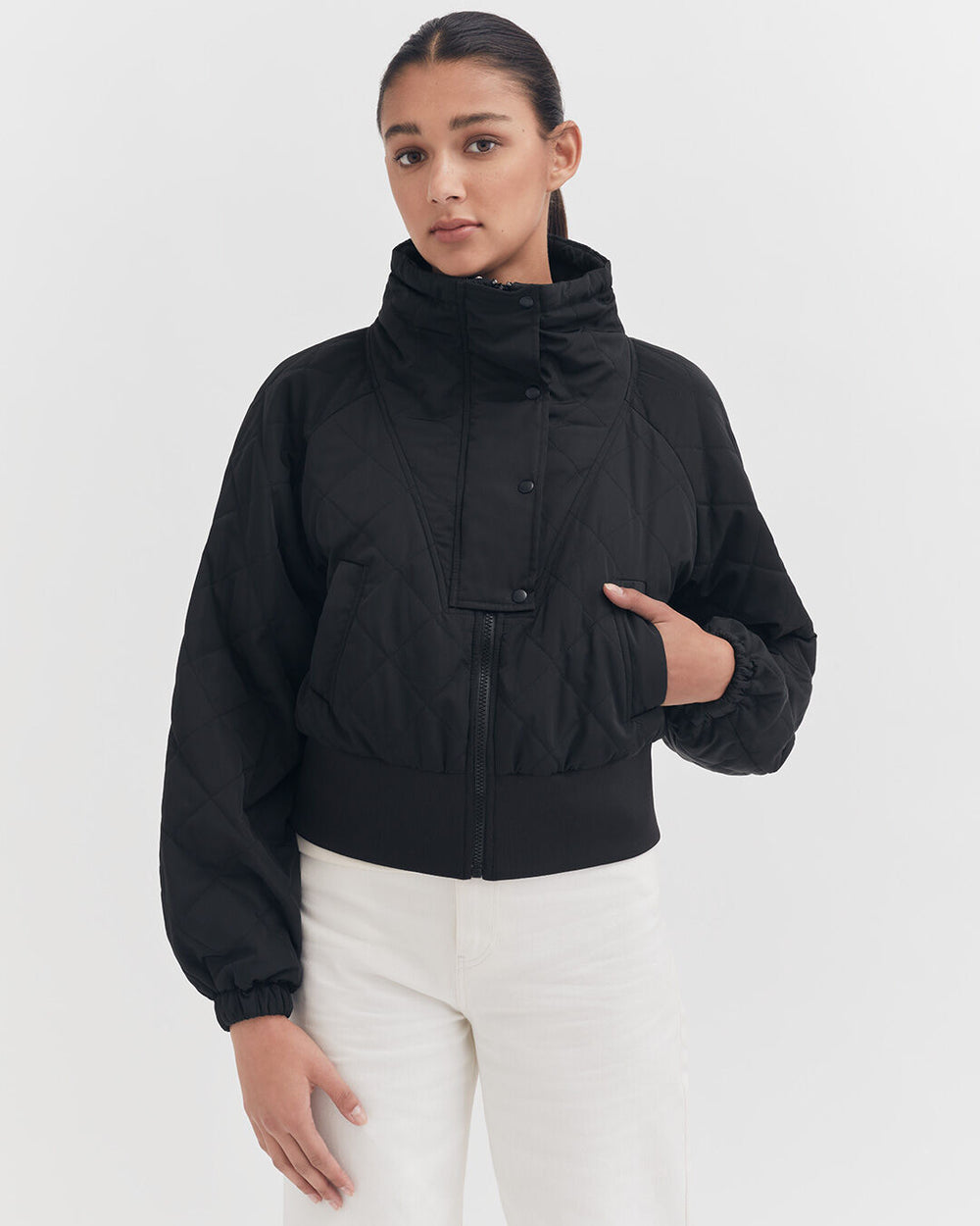 Woman standing in a jacket with her hand on her hip.