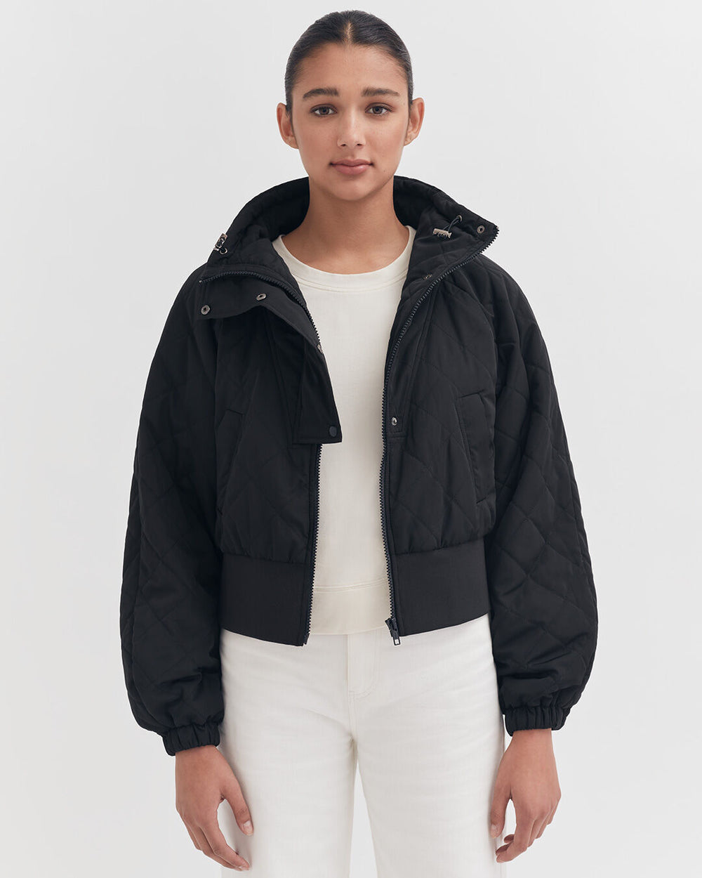 Woman in a jacket standing against a plain background.