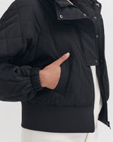 Person in a jacket pointing to its pocket.