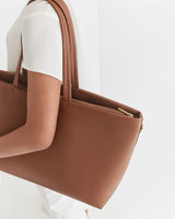 Person holding a large handbag over the shoulder.