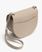 A shoulder bag with a curved flap and a long strap.