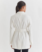 Woman from behind wearing a belted jacket and pants.