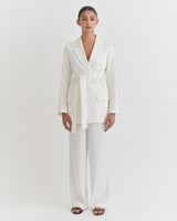 Woman standing in a belted blazer and trousers