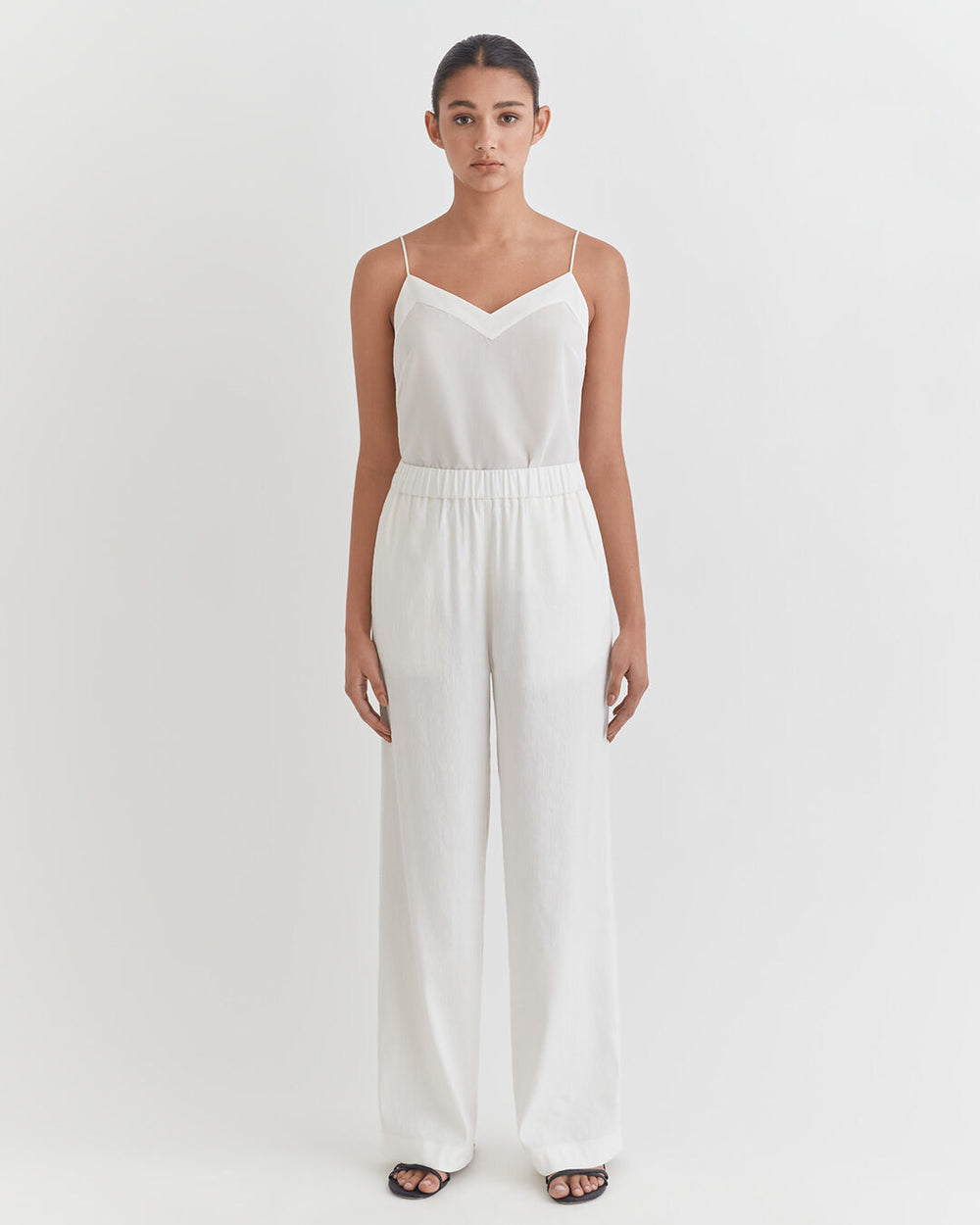 Woman standing in a jumpsuit with hands at her sides.