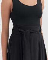 Woman wearing a tank top and skirt with a tied waistband.