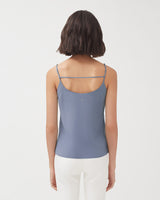 Woman seen from behind wearing a sleeveless top and pants.