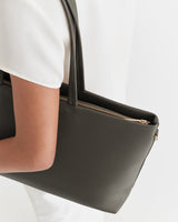 Person holding a handbag by their side