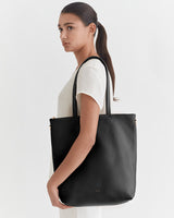 Woman carrying a large shoulder bag, looking to the side.