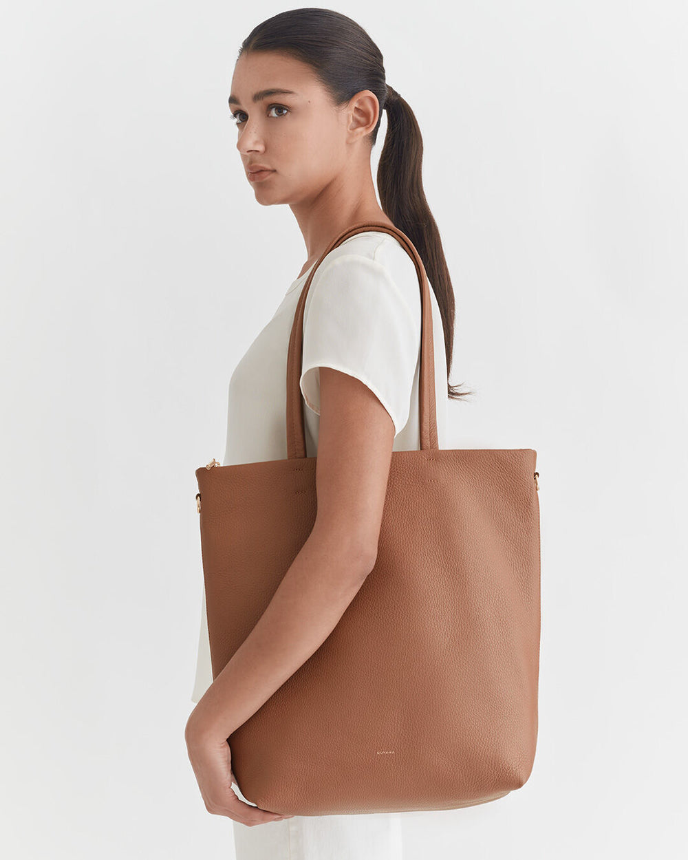Woman carrying a large tote bag over her shoulder.