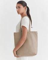 Woman with ponytail carrying a large tote bag over her shoulder