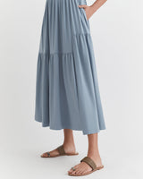 Woman standing in a long dress and sandals.