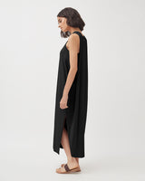 Woman walking in a sleeveless long dress with sandals.