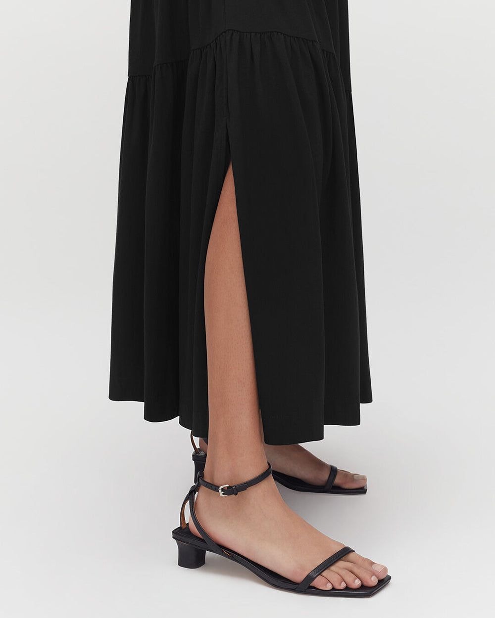 Person wearing sandals and a dress with a high side slit.