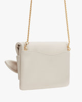 Purse with a chain strap and flap closure hanging against a plain background.