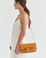 Woman holding a clutch with a chain, viewed from the side.