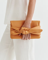 Person holding a clutch with a knotted design