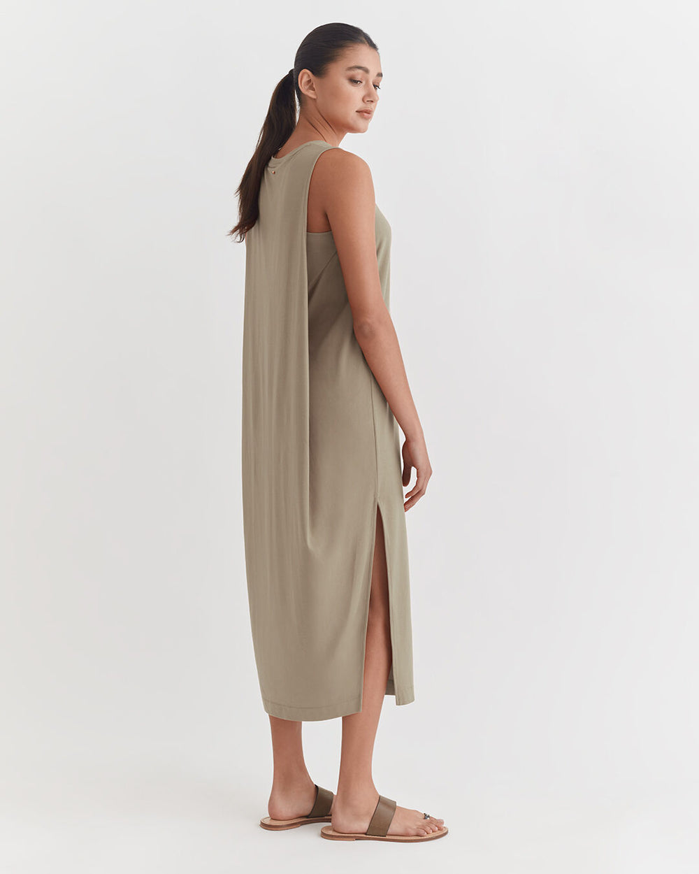 Drape-Back Dress Woman in a sleeveless long dress standing sideways, looking over shoulder.