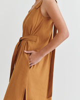 Woman in a sleeveless jumpsuit with a tie at the waist, partial view