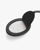 Open round luggage tag with a paper insert for contact information.