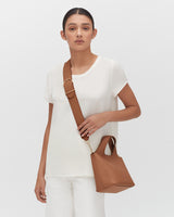 Woman standing with a shoulder bag.